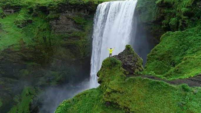男子高举在山顶上，站在瀑布前庆祝冰岛的旅行和冒险