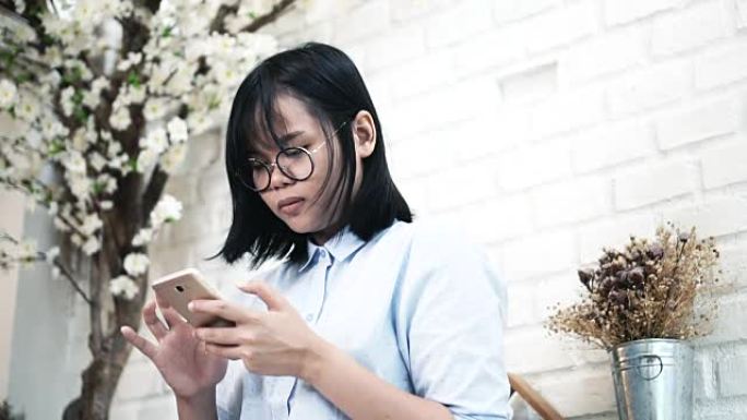 使用智能手机坐在现代合作空间，生活方式和休闲概念的亚洲女性的慢动作FHD镜头