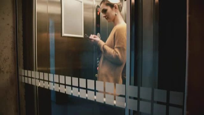 使用智能手机电子商务应用程序在透明电梯中骑行的年轻自信成功女商人的观点
