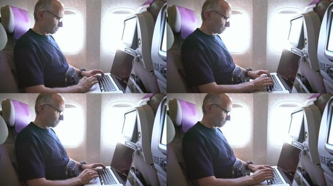 成熟的男人在飞机上使用笔记本电脑