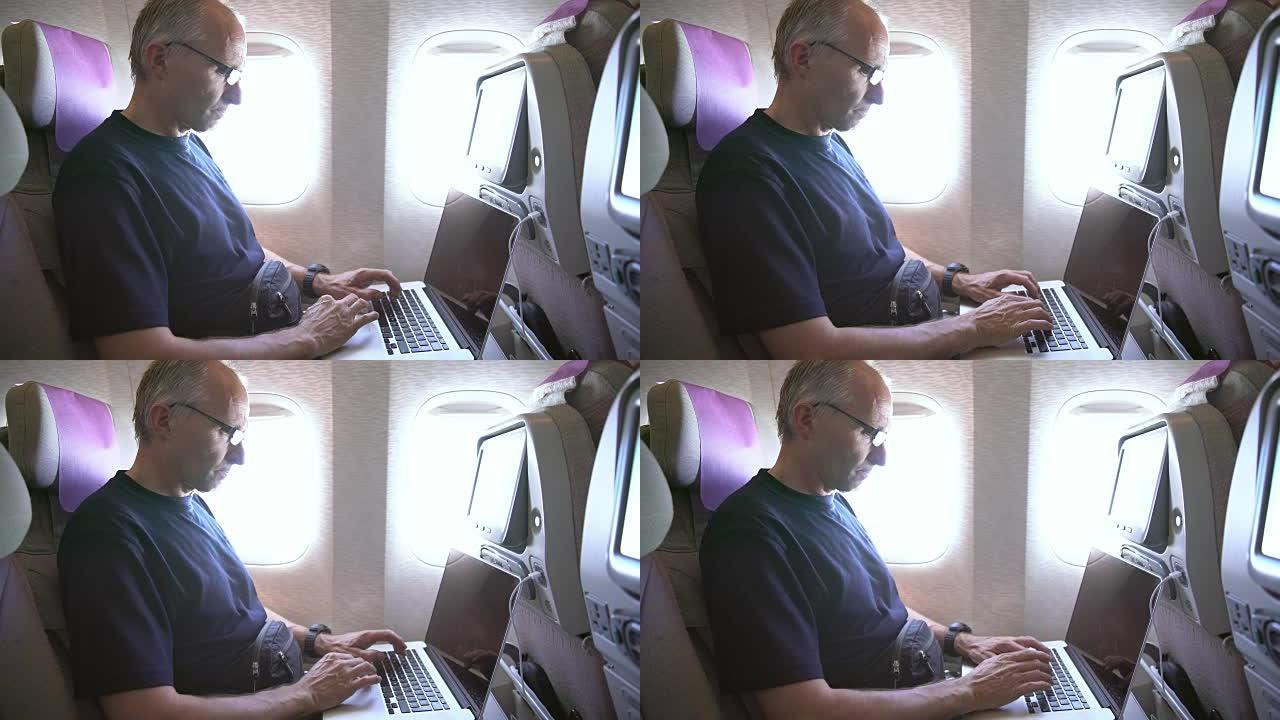 成熟的男人在飞机上使用笔记本电脑