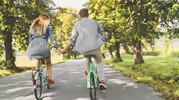 TS年轻夫妇在绿树成荫的乡间小路上骑自行车
