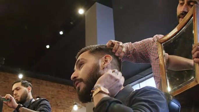 客户在理发师持有的镜子中检查理发