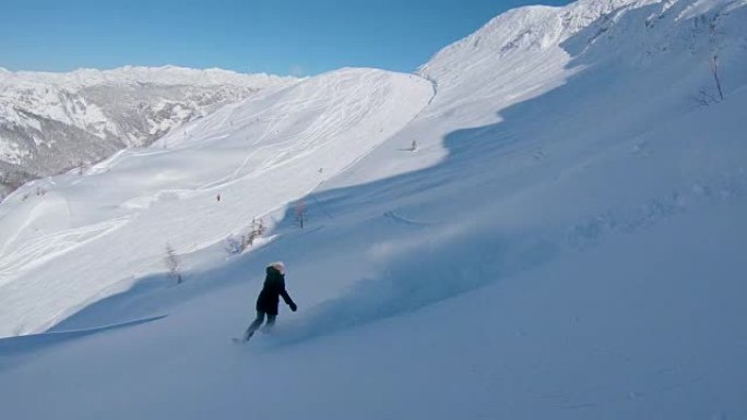 跟随: 滑雪板女孩从滑雪道上驶向滑雪胜地的山坡。