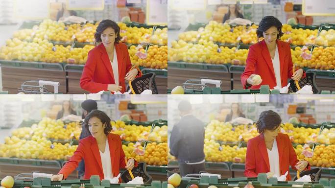 在超市: 美丽微笑的女人在新鲜农产品过道中选择有机水果并将其放入购物篮的肖像。高角度拍摄。
