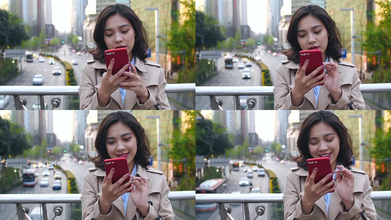 下午，在中国城市成都，在交通繁忙的天桥上，使用手机的年轻亚洲女性非常快乐