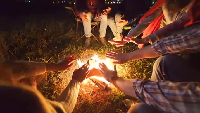 快乐的人们坐在篝火旁。晚上时间