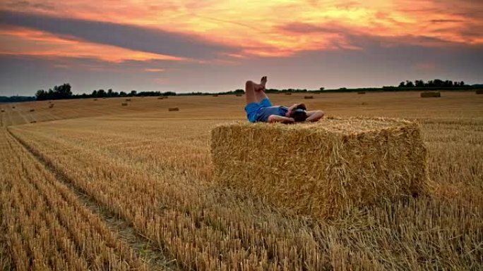 DS男子在日落时在草捆上放松