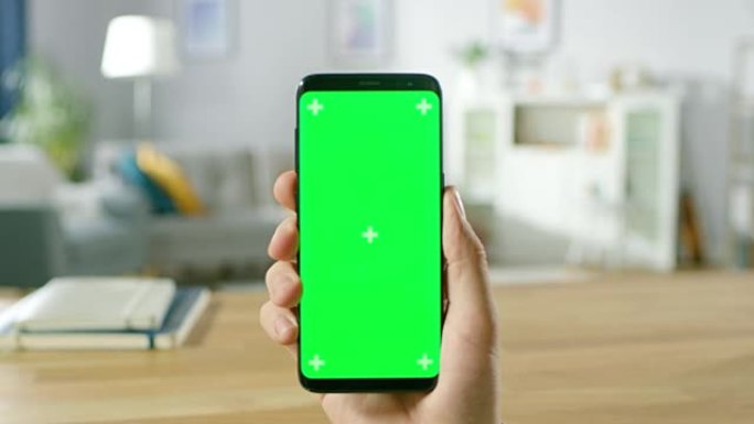 一个男人在现代绿色模拟屏幕智能手机上握着手势的特写镜头。用手指触摸手机色度键屏幕。