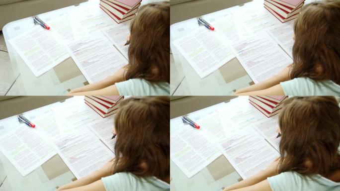 女孩在满是笔记和书籍的桌子后面学习
