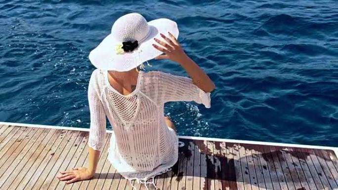 坐在船尾的遮阳帽的SLO MO女人