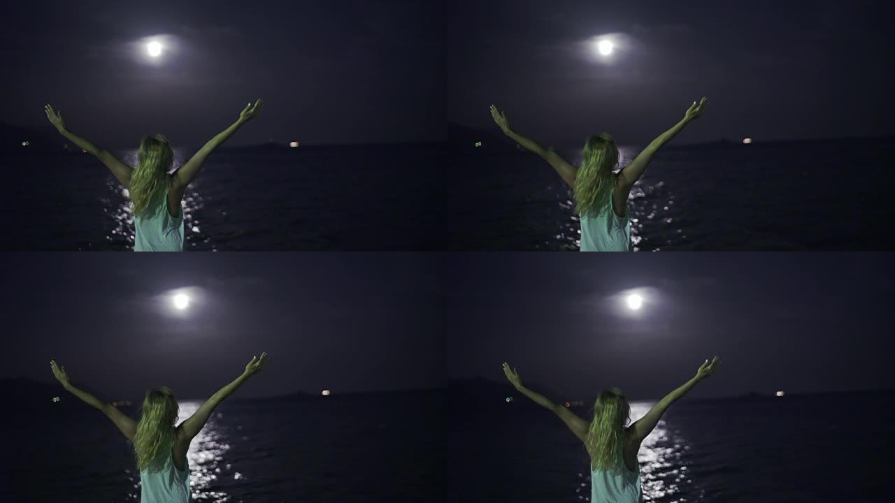 年轻女子在岸上祈祷。满月。