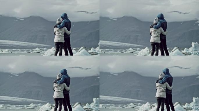 夫妇拥抱并看着冰川泻湖