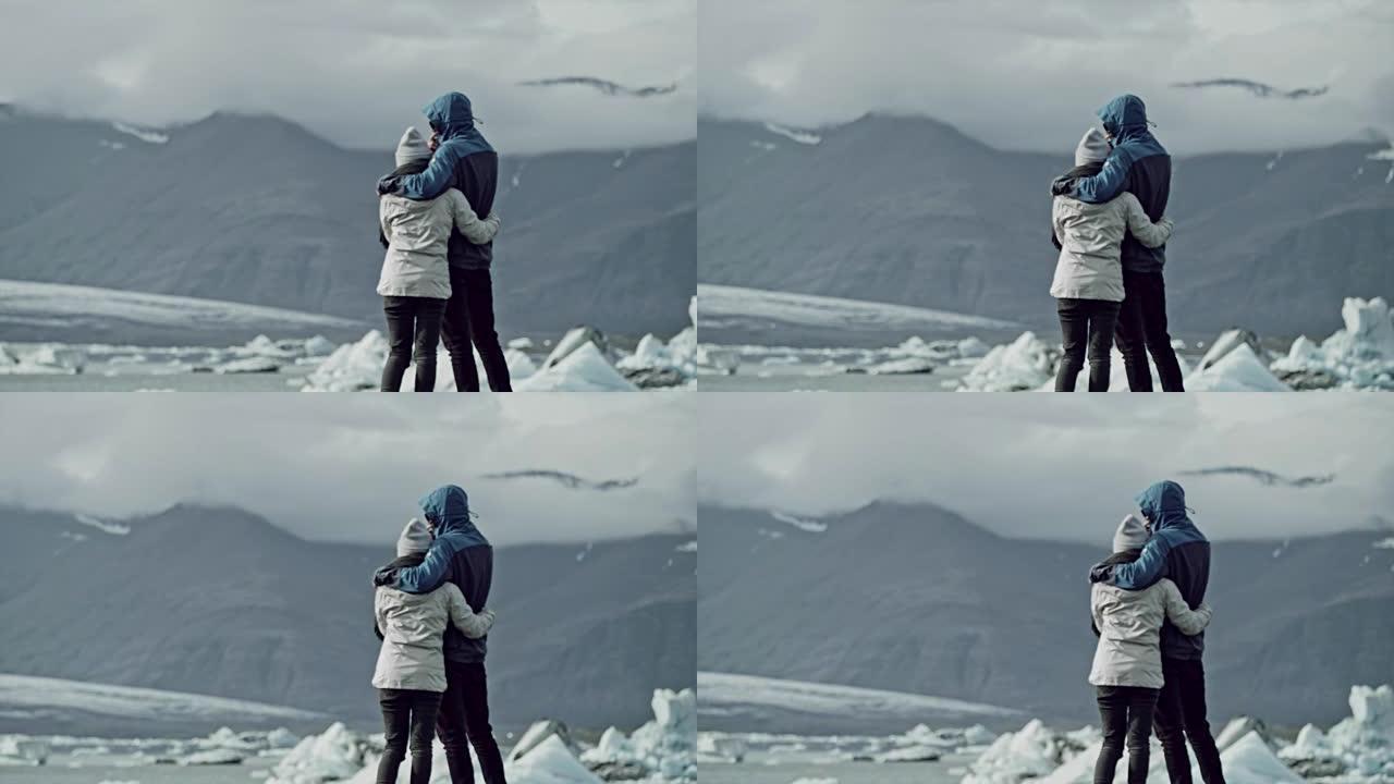 夫妇拥抱并看着冰川泻湖