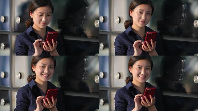 年轻的亚洲女商人在办公室窗户玻璃旁看着手机，慢动作4k
