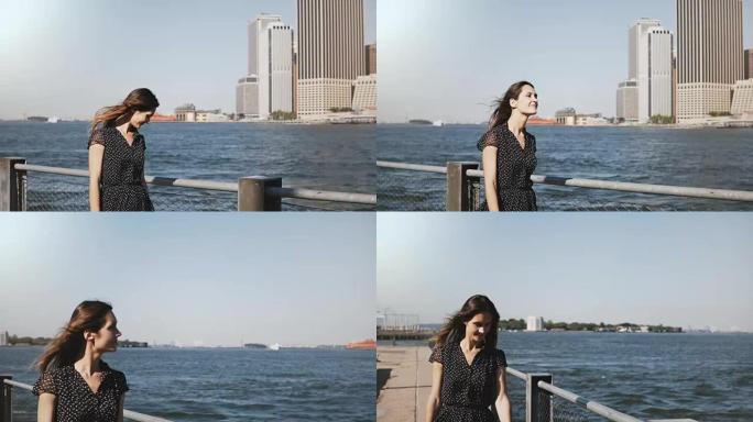美丽微笑的白人妇女，头发飞舞，沿着著名的纽约市金融中心河畔天际线行走