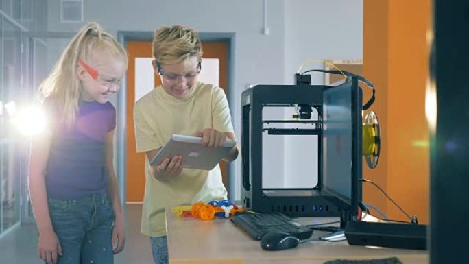 同学们在实验室中使用3D打印机时看着平板电脑。4K。