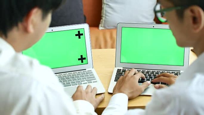 两名商人使用两台带有绿屏、色度键的笔记本电脑
