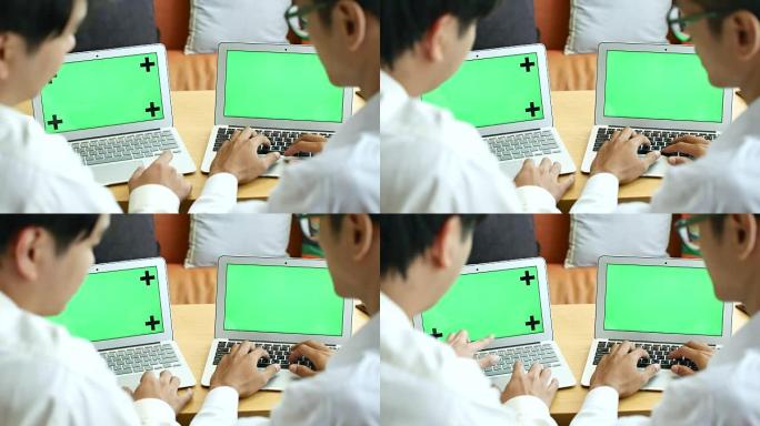 两名商人使用两台带有绿屏、色度键的笔记本电脑