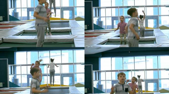 三个小孩在蹦床上跳跃