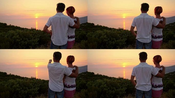 相爱的夫妇在日落时欣赏海景
