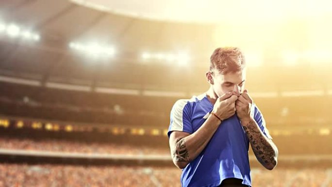 足球运动员庆祝胜利，并在职业体育场上快乐地亲吻他的t恤，而阳光普照