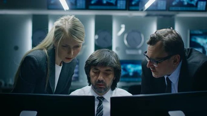在系统控制室的计算机上工作的男性和女性操作员。秘密政府机构分析师做研究，进行网络安全调查。