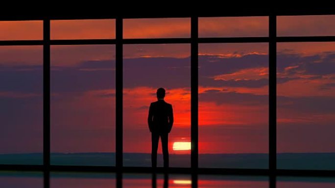 站在日落背景全景窗户附近的那个人。时间流逝