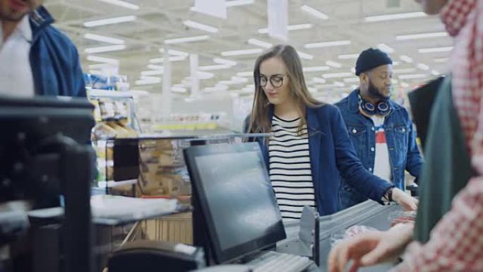 在超市: 收银台收银员扫描食品杂货和食品。客户将产品放置在输送线上。清洁现代购物中心。
