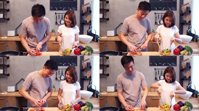 男人在厨房里切西红柿。美丽幸福的亚洲夫妇正在厨房做饭。年轻的亚洲夫妇在家里度过浪漫的时光。情侣家庭生