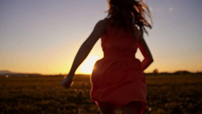 日落时在草地上奔跑的SLO MO女孩
