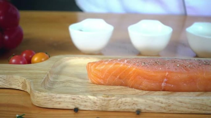 慢动作-美食厨师或烹饪用海盐和辣椒粉调味新鲜的熟食店鲑鱼鱼。