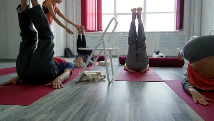 培训师帮助老年人在瑜伽垫上锻炼