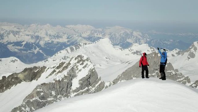 登山者在白雪覆盖的山峰上欢呼雀跃