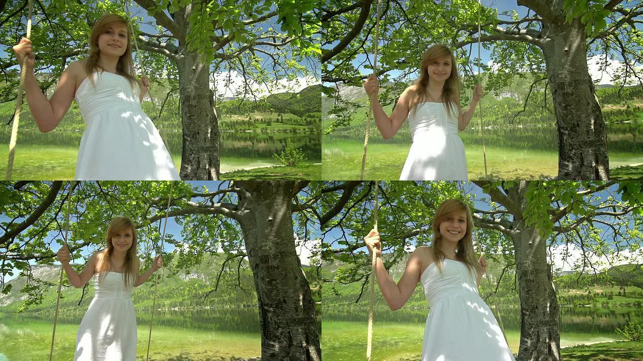 一个穿着白色连衣裙的女孩站在湖边荡秋千的绳子上
