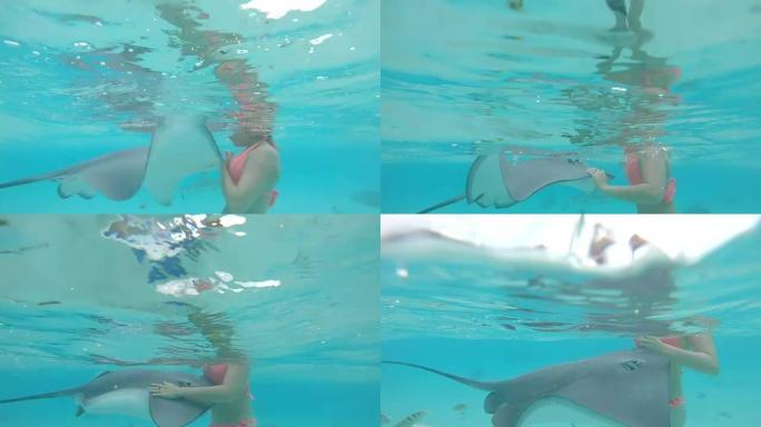 慢动作: 快乐的女孩在玻璃状的海洋中游泳会碰到顽皮的海射线。