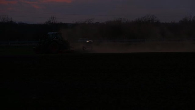 黄昏时拖拉机在耕地