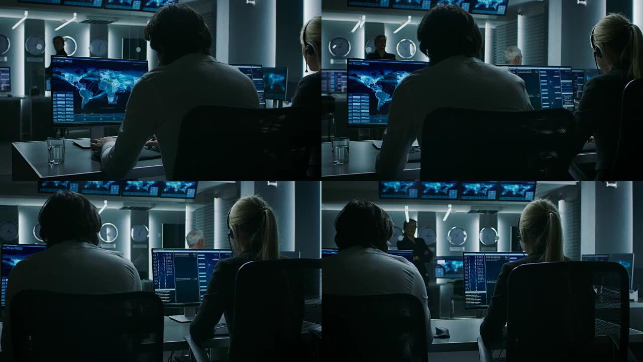 在个人计算机上工作的网络安全调度员的后视图，显示了充满特殊情报人员的系统控制室中的交通数据流。