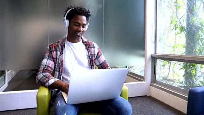 快乐的非洲裔美国人在办公室里用耳机和笔记本电脑进行视频会议