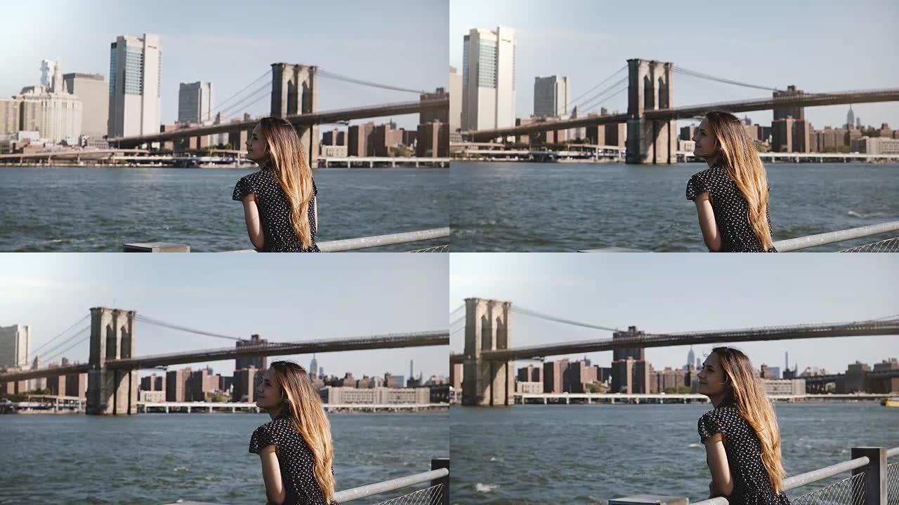 快乐微笑的欧洲女人的平移景色，头发飞舞，享受着著名的纽约天际线和布鲁克林大桥的景色