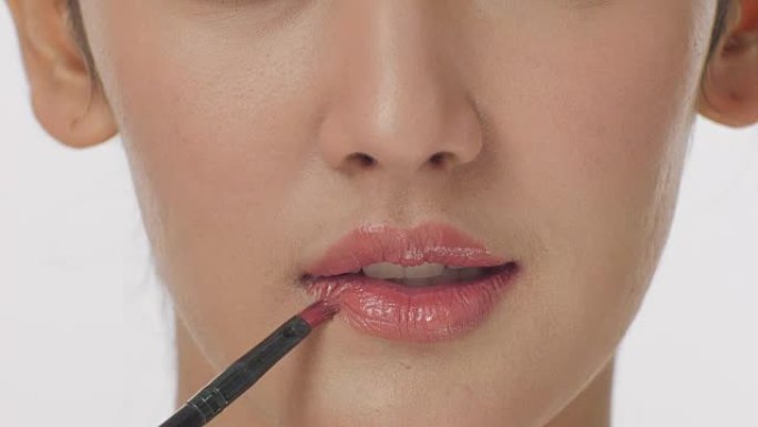化妆师在性感嘴唇上涂口红的特写肖像有魅力的女人。化妆嘴唇。美丽和时尚概念。