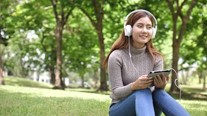 戴着耳机的亚洲女人在公园听音乐