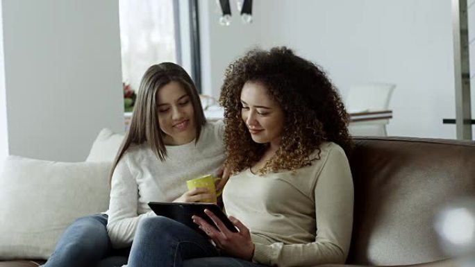 两个年轻朋友在使用数字平板电脑时喝咖啡