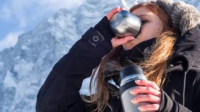 女人在雪山的热水瓶里喝酒