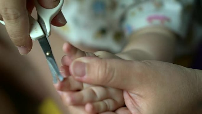 母亲用不锈钢指甲钳切割婴儿的脚趾甲。特写白色背景，选择性聚焦，医疗保健概念。