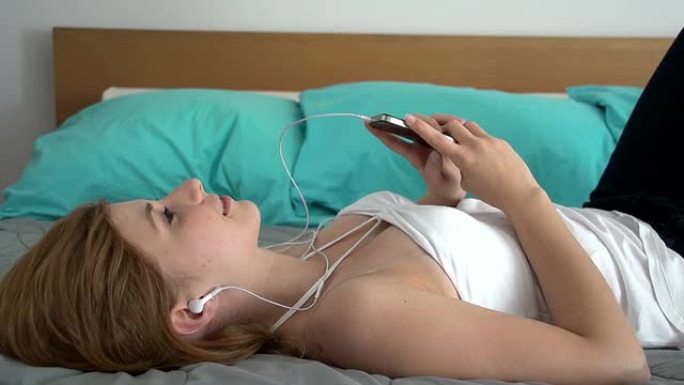 年轻的女人躺在床上听音乐