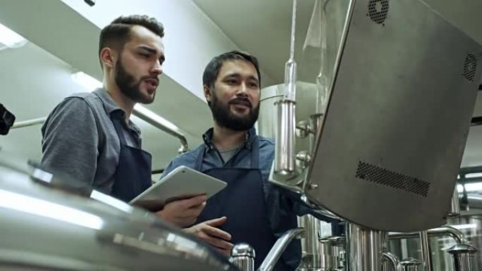 啤酒酿造工人操作机器和使用平板电脑