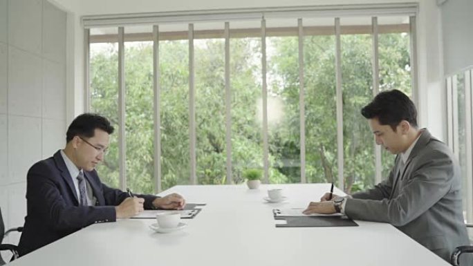 慢动作-求职会议后握手达成协议。两位亚洲自信的商人在办公室开会时握手，成功，交易，问候和合作伙伴概念