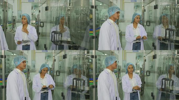 两名工程师在一家工厂的白色均匀控制生产过程。饮用水和饮料的生产