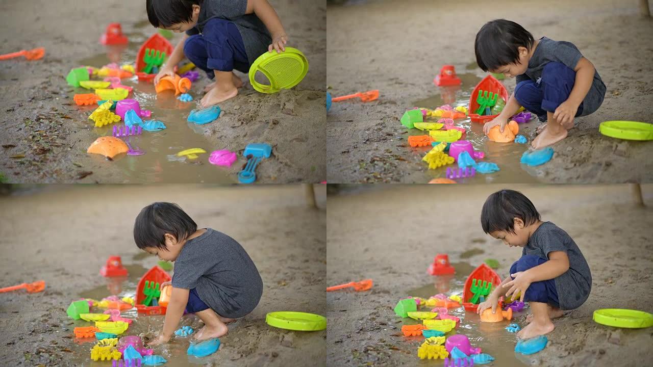 小男孩在泥坑里玩玩具。